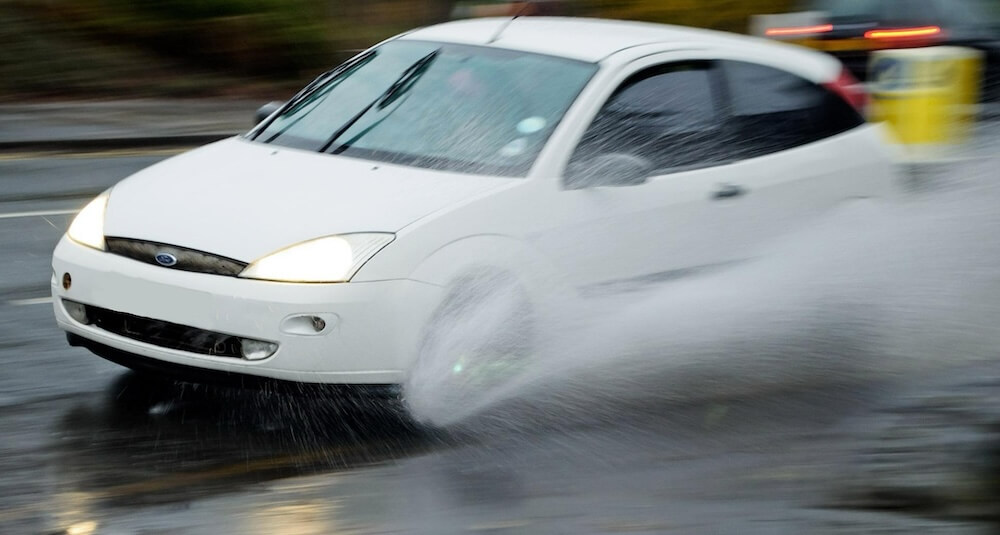 Bei nasser Strasse wirkt die Wasserschicht wie ein Schmiermittel und verlängert den Bremsweg